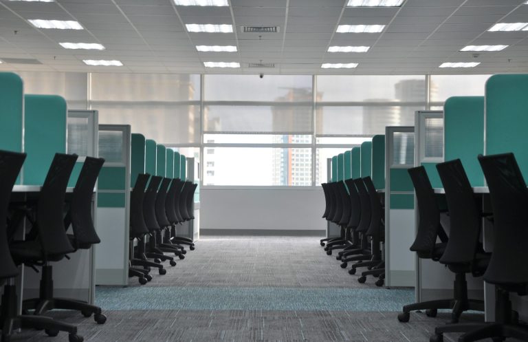 Bureaux modernes avec chaises noires et cloisons turquoises, lumineux et spacieux.