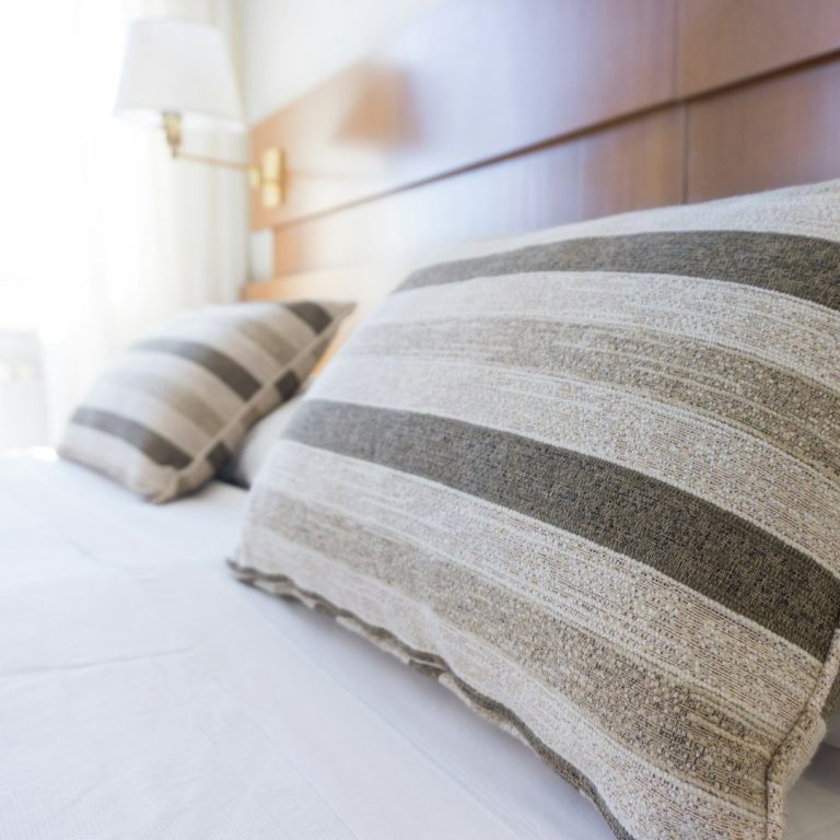 Oreillers à rayures sur un lit avec un mur en bois en arrière-plan.