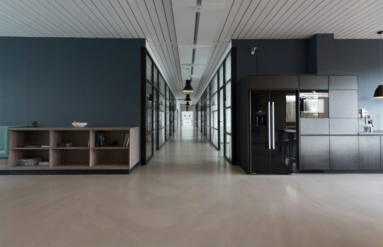 Intérieur moderne d'un couloir de bureau avec des murs en verre et un coin cuisine.